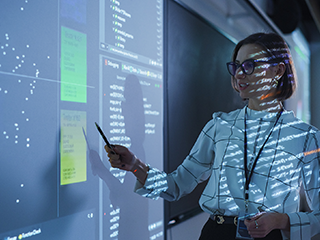 female professor pointing to white board with digital overlay projected onto her